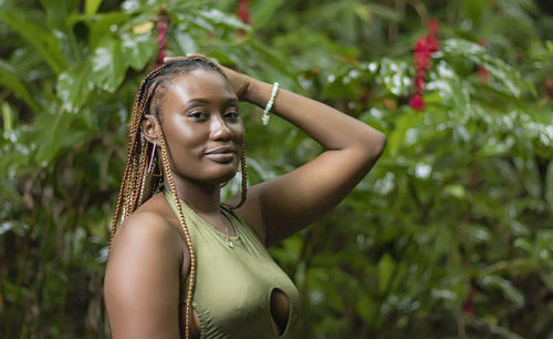 Portrait of young woman standing against plants