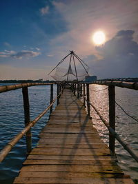 Pier over sea against sky during sunset