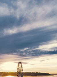 View of ferris wheel against cloudy sky