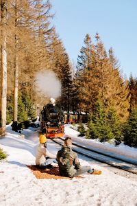 Rear view of people sitting on snow covered plants