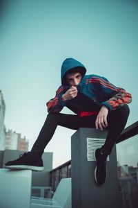 Full length of man sitting in city against clear sky