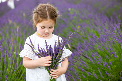 Girl holding flower standing in field