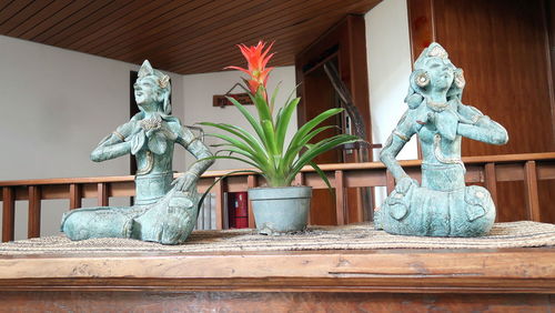 Statue and potted plant on table against building