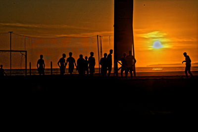 Silhouette people by sea against sky during sunset