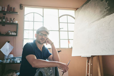 Portrait of man working as painter holding brush in workshop