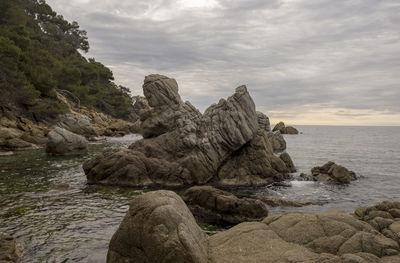 Rock formation on sea shore against sky