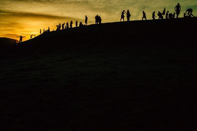 Silhouette people standing on beach during sunset
