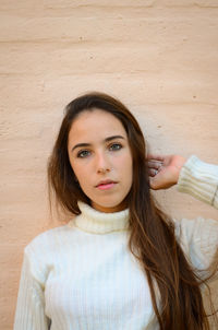 Portrait of a beautiful young woman against wall