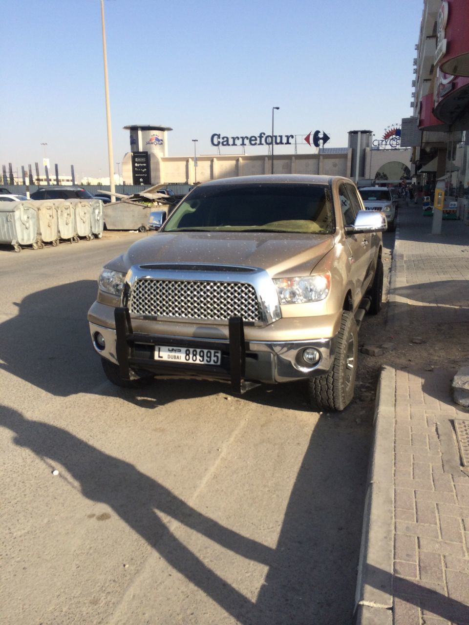 transportation, land vehicle, mode of transport, car, clear sky, built structure, architecture, sunlight, building exterior, street, shadow, road, day, stationary, travel, outdoors, parking, incidental people, sky, city