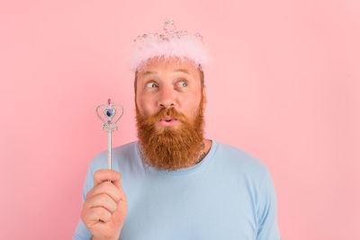 Portrait of man holding mask against gray background