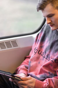 Young man reading e-book when he traveling by train. man sits at the window and using digital tablet