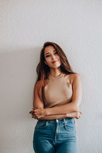 Portrait of a beautiful young woman standing against wall