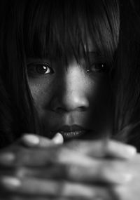 Close-up portrait of young woman with hands clasped