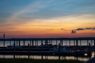 Silhouette boats moored at harbor during sunset