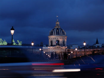 Light trails against institut de france and cloudy sky at dusk