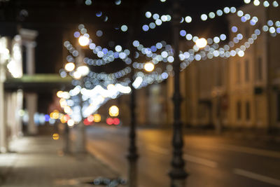 Defocused image of illuminated lights on city street at night