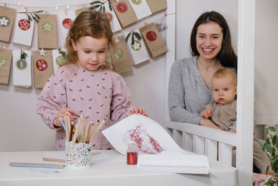 Toddler child writing christmas letter and doing advent calendar tasks in kids room. festive family