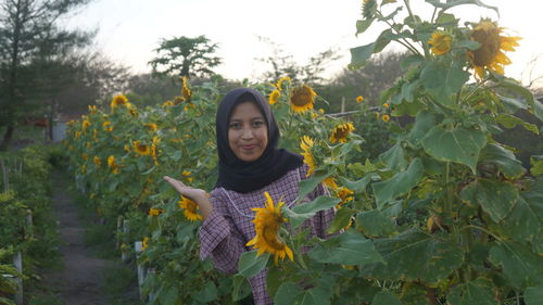 Woman standing by sunflower against sky