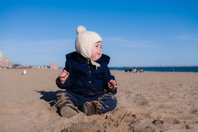 Extatic young boy is playing in the sand during in cold weather