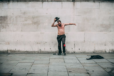 Full length of shirtless man standing against wall