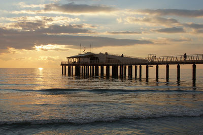 Pier over sea against sky during sunset