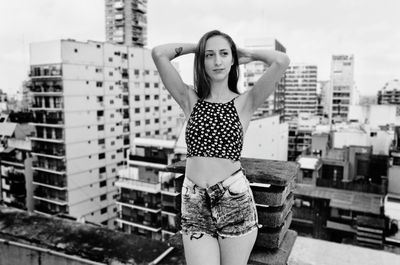 Young woman standing against buildings in city