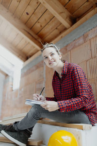 Woman working while sitting against wall