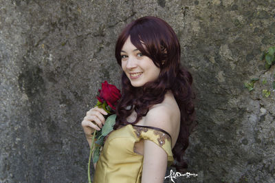 Portrait of smiling young woman against wall