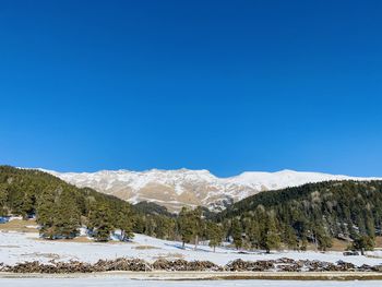 Scenic view of snowcapped mountains against clear blue sky