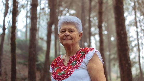 Portrait of senior woman against trees in forest