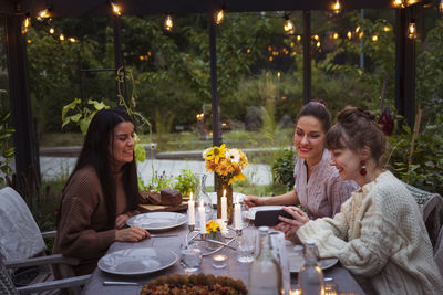 Smiling female friends sitting at table in greenhouse