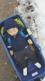 High angle view of toddler sleeping in baby carriage on footpath