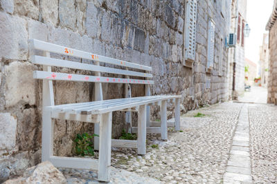 Empty benches on footpath against building