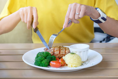 Midsection of woman having food at table