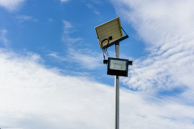 Small solar panel for light in street or park with white clouds and blue sky. 