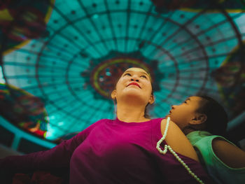 Low angle view of smiling mother and daughter looking up