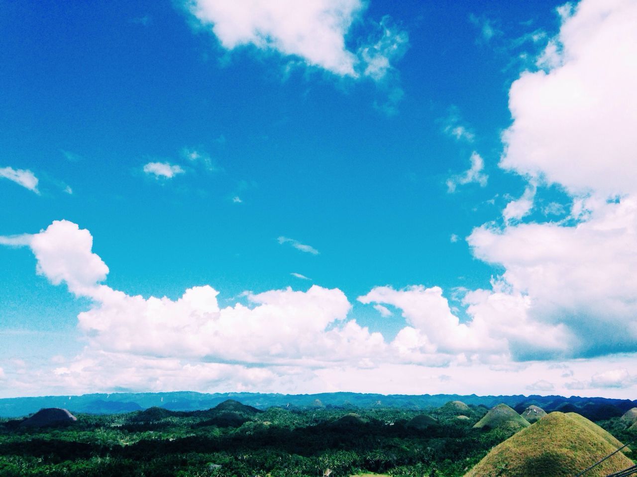 sky, landscape, tranquil scene, tranquility, scenics, beauty in nature, blue, cloud - sky, mountain, cloud, nature, horizon over land, field, non-urban scene, mountain range, cloudy, idyllic, remote, grass, day