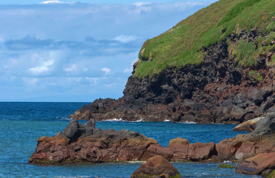 Rock formations by sea against sky