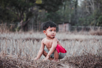Portrait of cute boy sitting on land