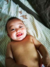 Portrait of cute baby girl lying on bed