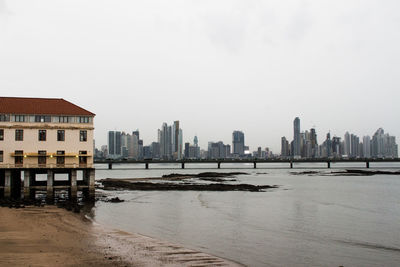 Buildings by sea against clear sky