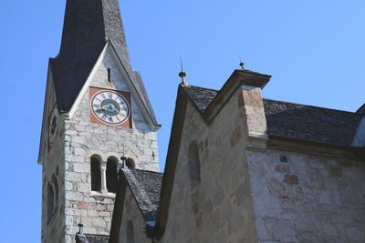 Low angle view of clock tower amidst buildings against clear sky