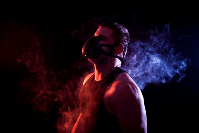 Young man smoking cigarette against black background