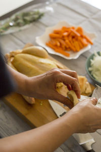 Cropped hands of woman preparing chicken in kitchen