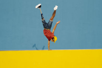 Man practicing handstand on multi colored wall
