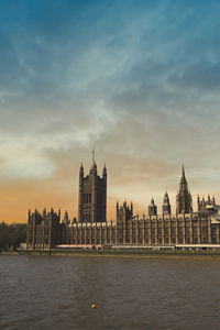 River and buildings against sky during sunset