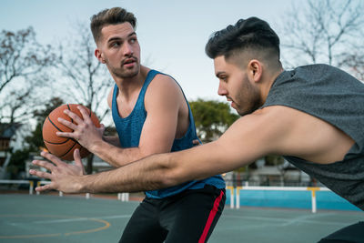 Close-up of men playing basketball outdoors