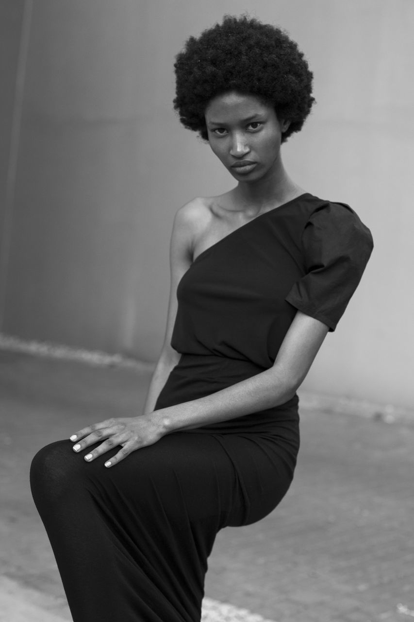 one person, adult, black, women, young adult, curly hair, portrait, fashion, hairstyle, black and white, elegance, clothing, sitting, photo shoot, looking at camera, white, female, monochrome photography, lifestyles, person, monochrome, indoors, glamour, dress, three quarter length, haute couture, arts culture and entertainment, short hair, looking, standing