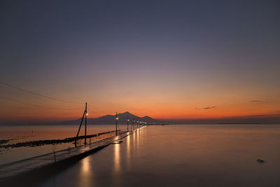 Pier over sea against sky during sunset