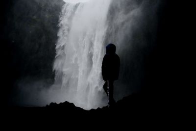 Rear view of silhouette man standing on mountain against sky